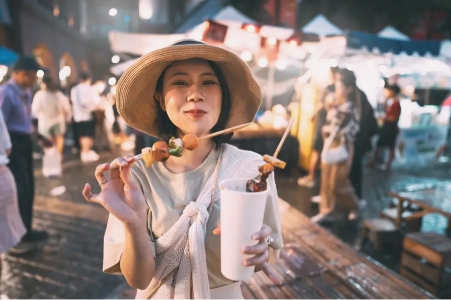 Phụ nữ châu Á thưởng thức đồ ăn xiên nướng tại chợ đêm ngoài trời